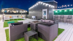 An outdoor patio with wicker furniture, a fire pit, and string lights. - Huge 4 Bedroom Home 14 Big Beds Rooftop Deck (Nashville)