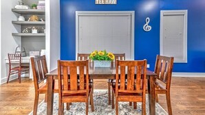A dining area with a blue accent wall, a white door, and a decorative treble clef. - Huge 4 Bedroom Home 14 Big Beds Rooftop Deck (Nashville)