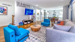 A modern living room with a flat-screen TV, blue and gray sofas, a wooden coffee table, and a patterned rug. - Huge 4 Bedroom Home 14 Big Beds Rooftop Deck (Nashville)