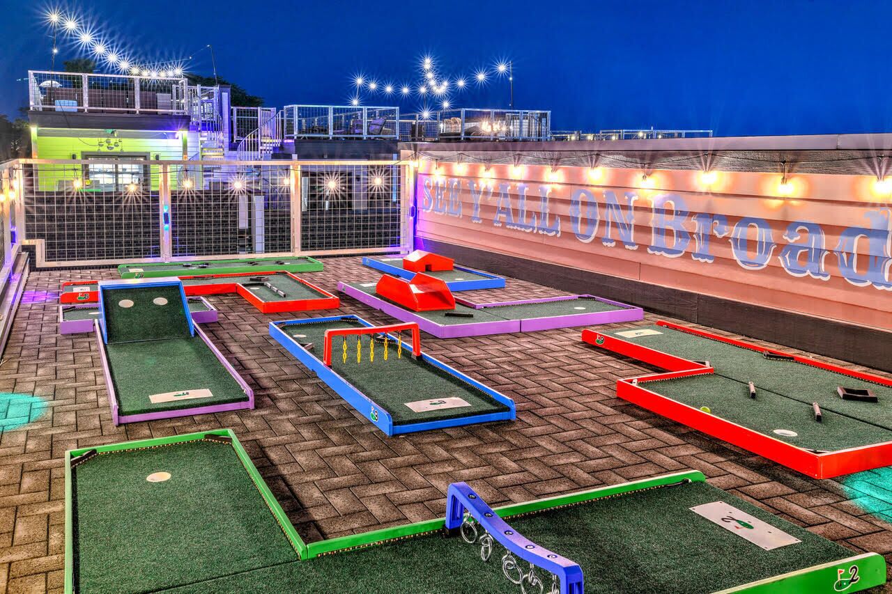Un campo de minigolf con varias pistas y un cartel que dice 'SEY FALLO ON BROADWAY'.