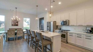 Una cocina moderna con armarios blancos, una isla central e iluminación colgante.