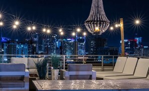 A rooftop lounge with a city skyline view, string lights, and a decorative chandelier. - Rooftop Pool Table Gulch! City Views! 15 beds! (Nashville)