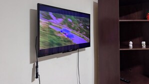 A flat-screen TV mounted on a white wall, connected to a power outlet. - Surbackpackers (Santa Cruz)
