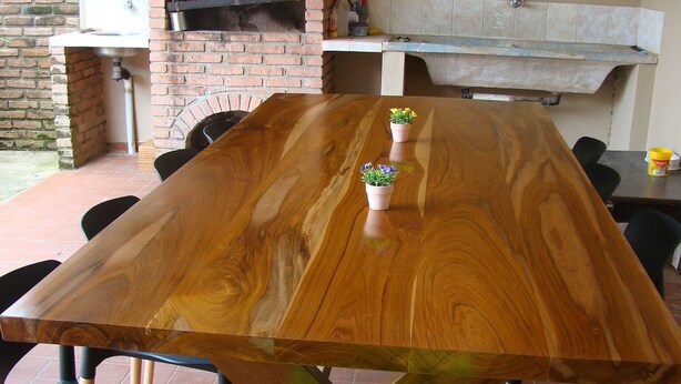 A wooden dining table with chairs, a brick oven, and a tiled floor. - Surbackpackers (Santa Cruz)