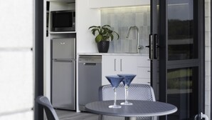 Une cuisine moderne équipée d’un lave-vaisselle, d’un four à micro-ondes et agrémentée d’une plante en pot. On y trouve une table ronde avec deux chaises et deux verres à martini.