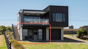 Une maison moderne à deux étages, dotée d’un balcon et d’un garage.