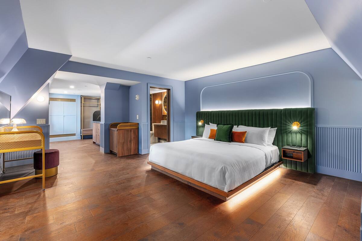 Um quarto moderno com uma cama grande, uma mesa de cabeceira de madeira e uma escrivaninha com abajur.