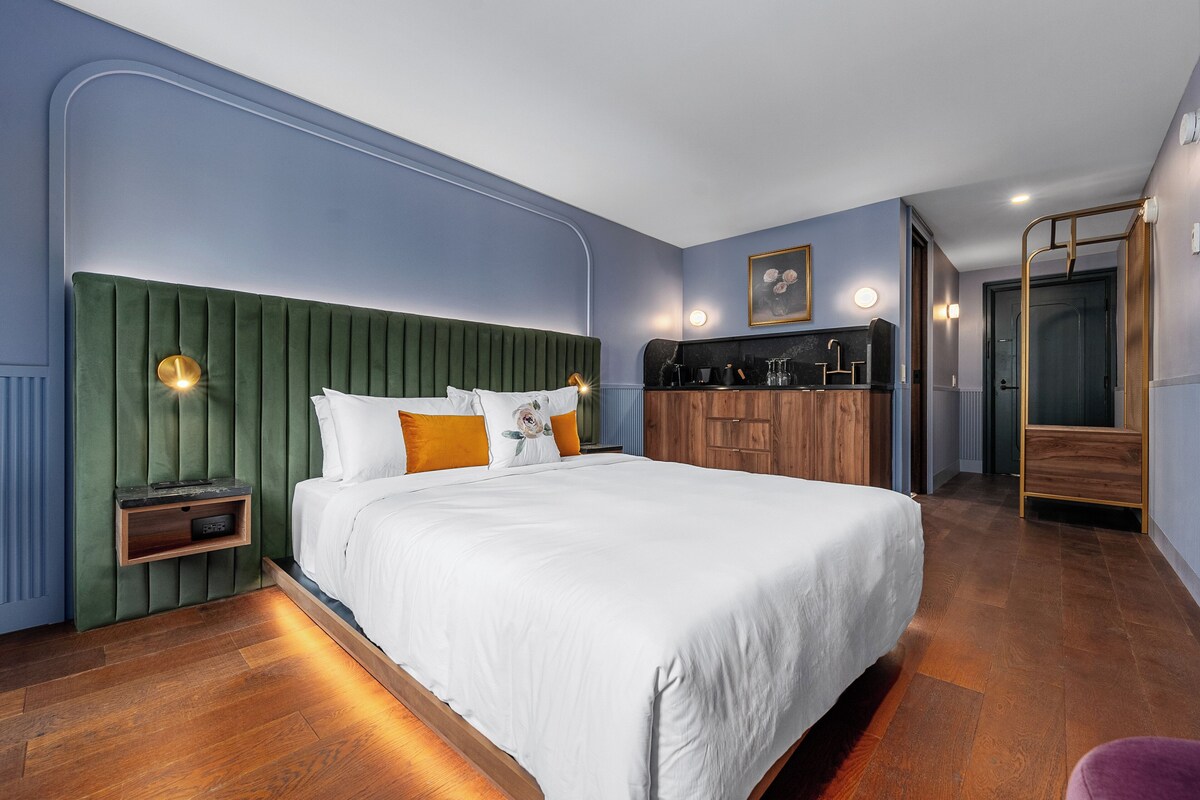 A modern bedroom with a green upholstered headboard, a wooden nightstand, and a white bed.