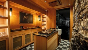 A modern kitchen with wooden cabinetry, a checkered floor, and a stone accent wall. - Hotel Maurice (Québec City)
