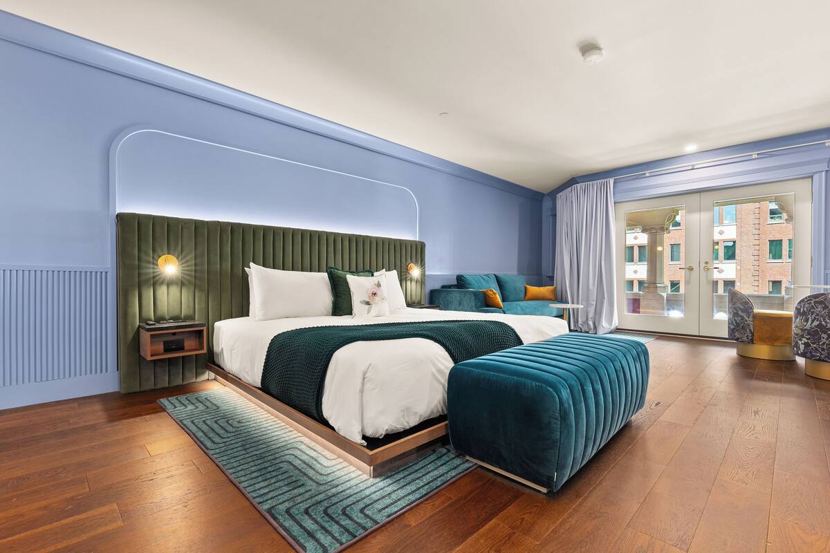 Quarto moderno com uma cama grande, mesa de cabeceira e vista para o exterior através de uma porta de vidro.