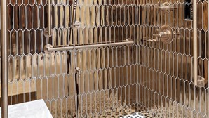 A bathroom with a metallic honeycomb wall, a white bathtub, and a patterned floor. - Hotel Maurice (Québec City)