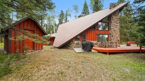 A rustic cabin with a sloped roof, a stone foundation, and a red exterior. - A-Frame at Arrowhead (Cimarron)
