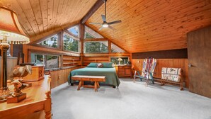 A cozy wooden cabin bedroom with a bed, a desk, and skis leaning against the wall. - A-Frame at Arrowhead (Cimarron)