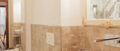 A bathroom with a toilet, bidet, and a large sink with a mirror above.