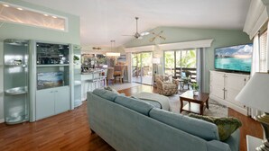 A spacious living area with a sofa, dining table, and kitchen area with a TV. - Private Waterfront Oasis w/Heated Pool/Hot Tub & Dock, Close to Everything! (Naples)