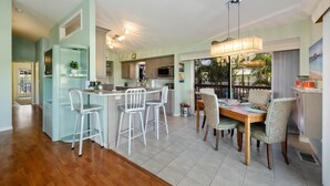 A modern kitchen with a central island, bar stools, and a dining table with chairs. - Private Waterfront Oasis w/Heated Pool/Hot Tub & Dock, Close to Everything! (Naples)