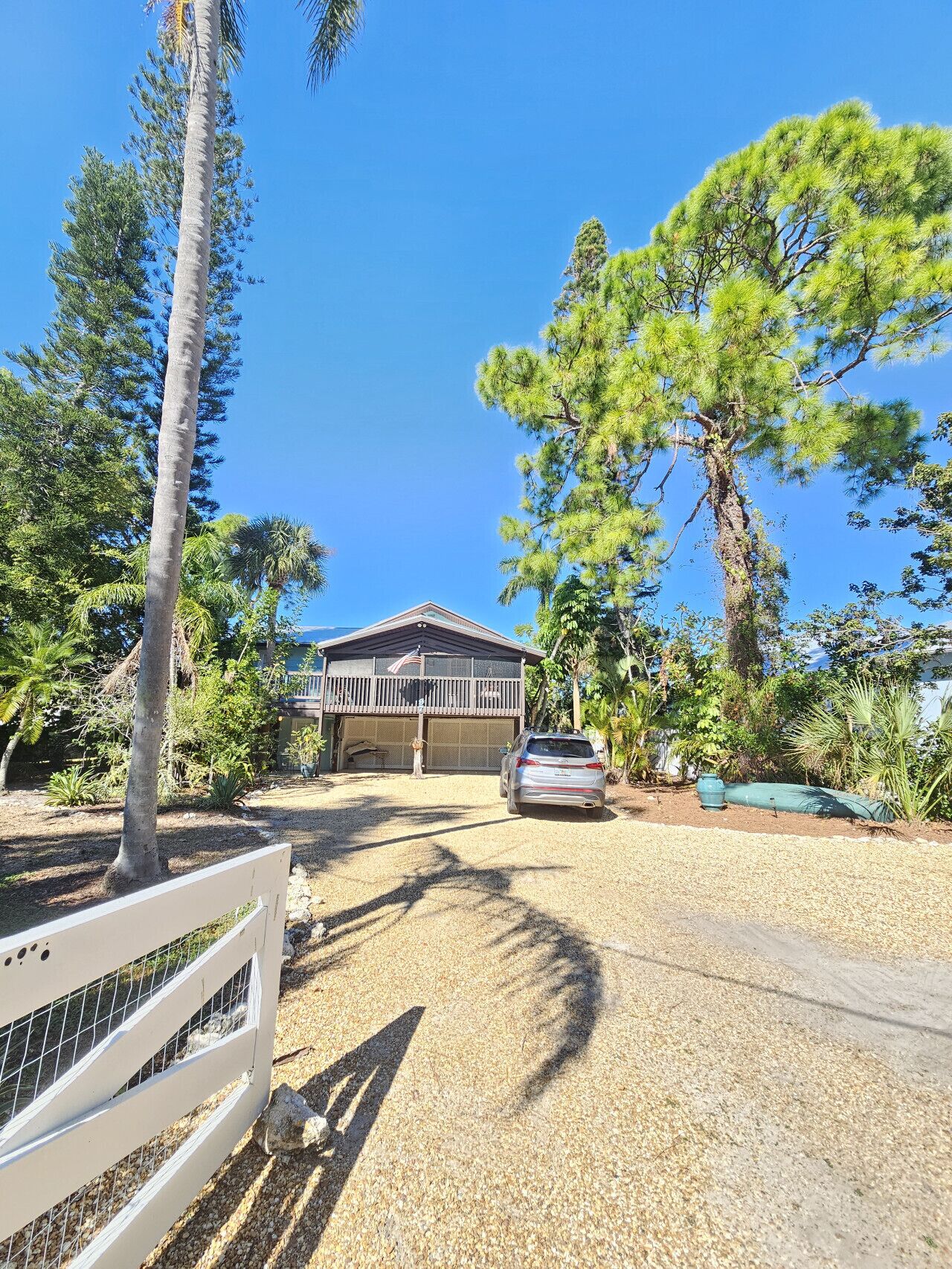 A house with a garage, surrounded by trees and a gravel driveway.
