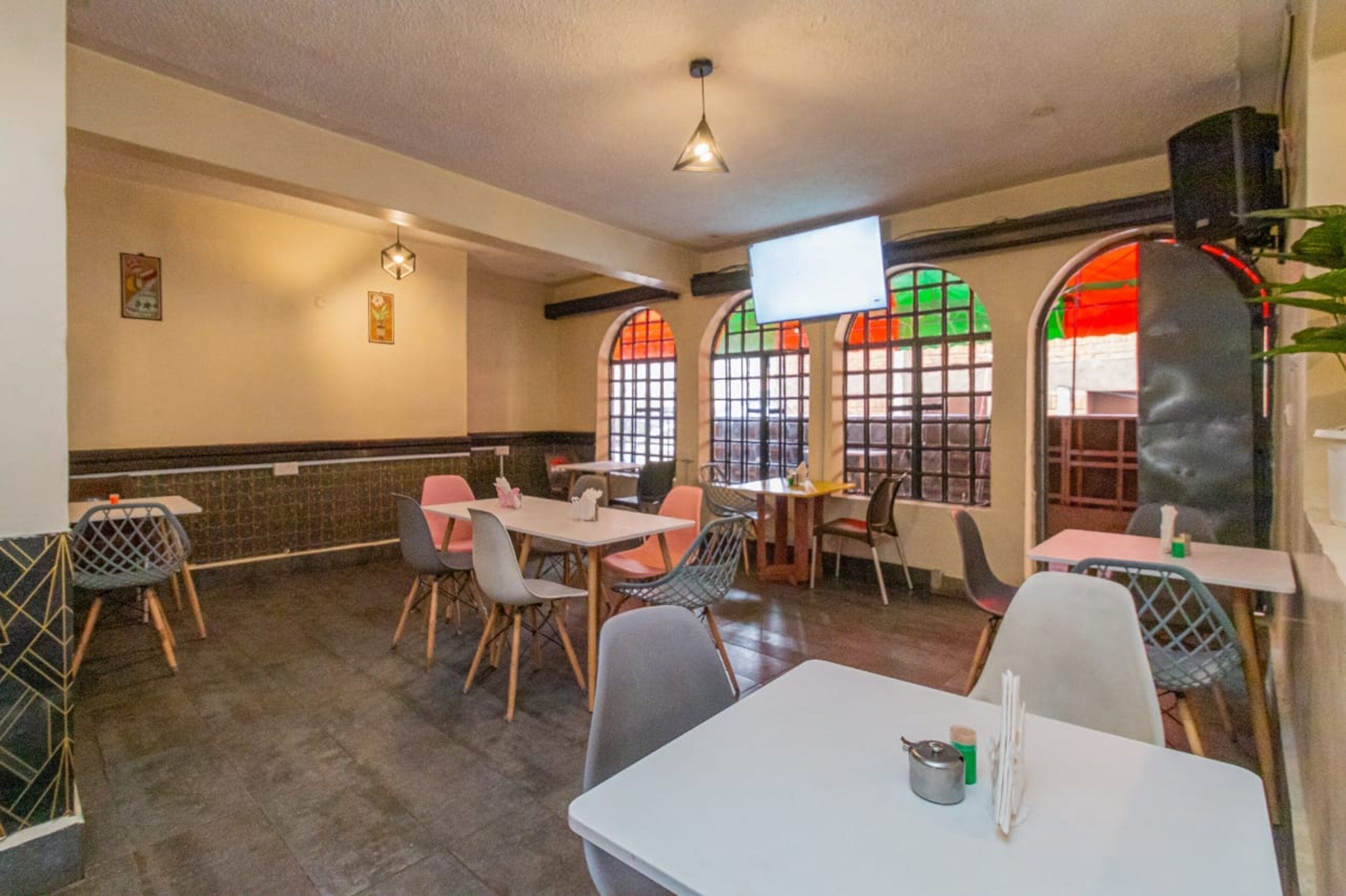 Een restaurant met een combinatie van houten en metalen stoelen, witte tafels en een betegelde vloer.