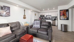 Ein modernes Wohnzimmer mit zwei Sofas, einem Couchtisch und einer Küche im Hintergrund.