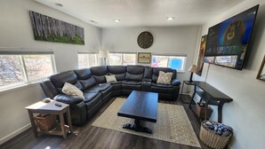 Een moderne woonkamer met een modulaire bank, een salontafel en een aan de muur bevestigde televisie.