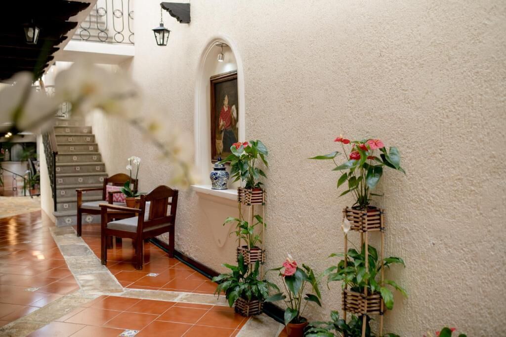 A cozy indoor patio area with a wooden chair, potted plants, and a tiled floor.