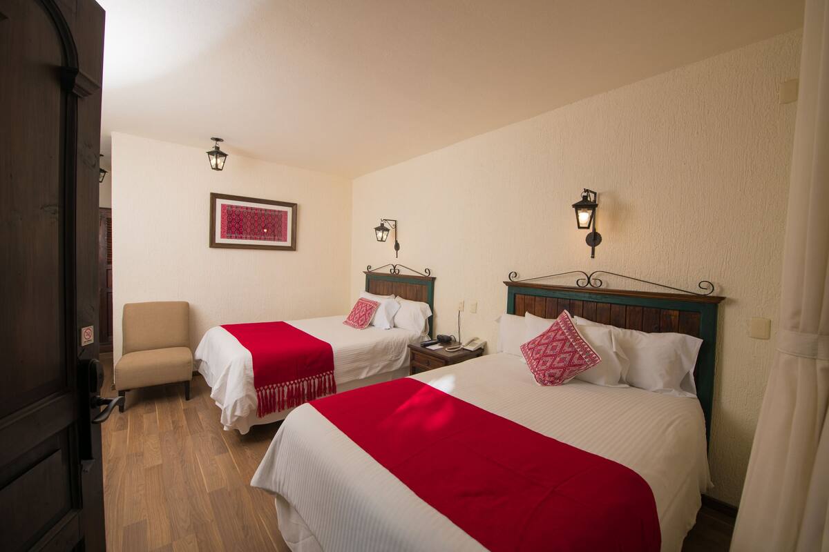 Una habitación de hotel con dos camas, una silla y una mesita de noche.
