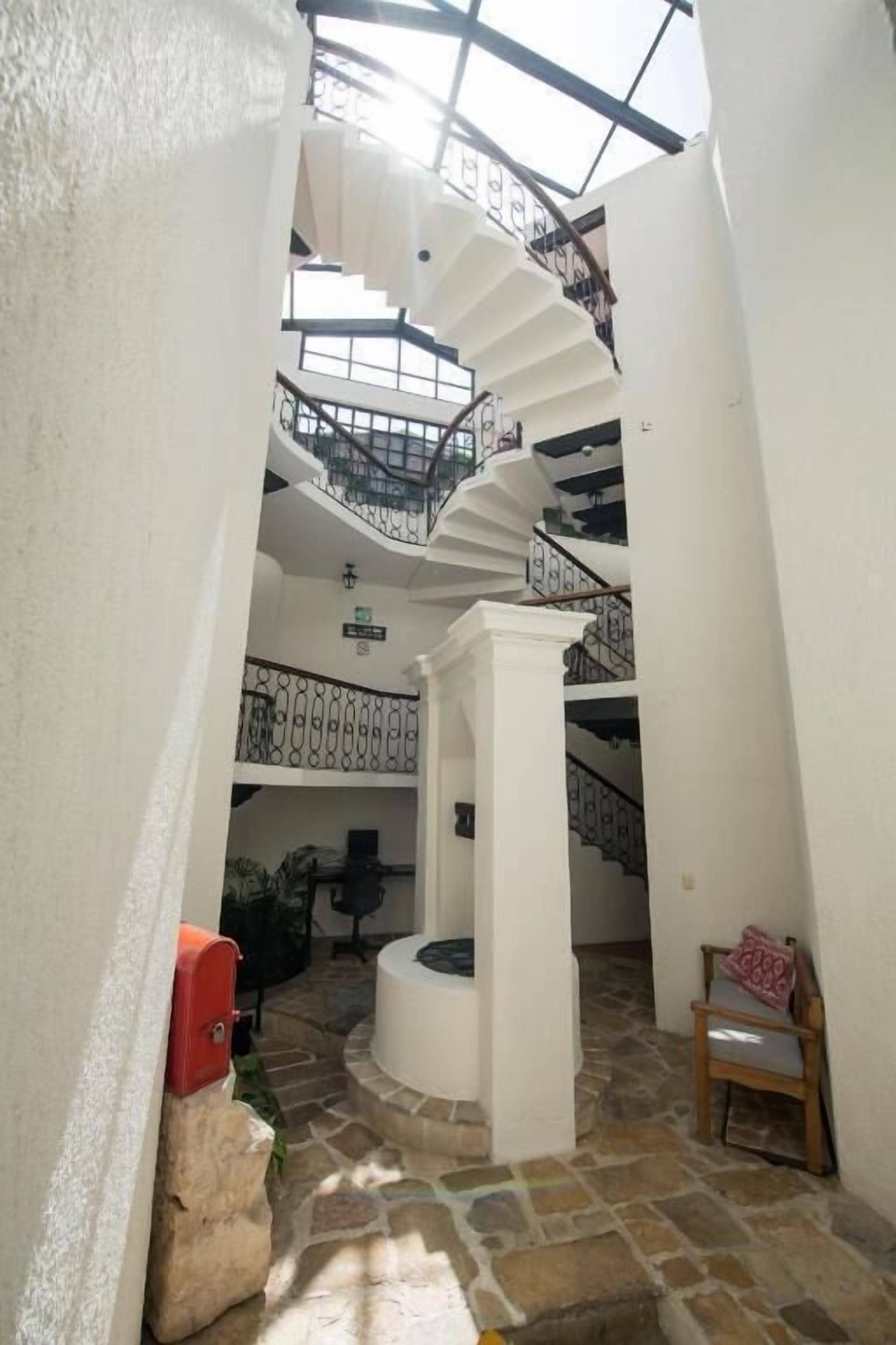 Ein mehrgeschossiges Interieur mit einer zentralen Wendeltreppe, Steinböden und einem Oberlicht.