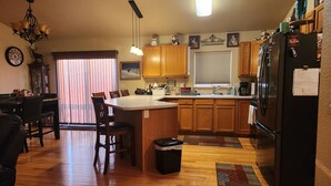 A kitchen with wooden cabinets, a refrigerator, and a dining area with chairs and a table. - South Dakota Black Hills rental (Whitewood,)