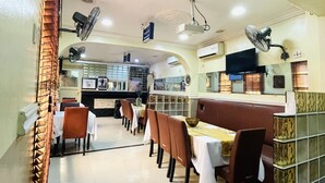 A restaurant with tables and chairs, a counter, and a television on the wall. - NUMBER ELEVEN HOTEL (Lagos)