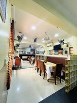 Um restaurante com mesas, cadeiras, um balcão e uma televisão na parede.
