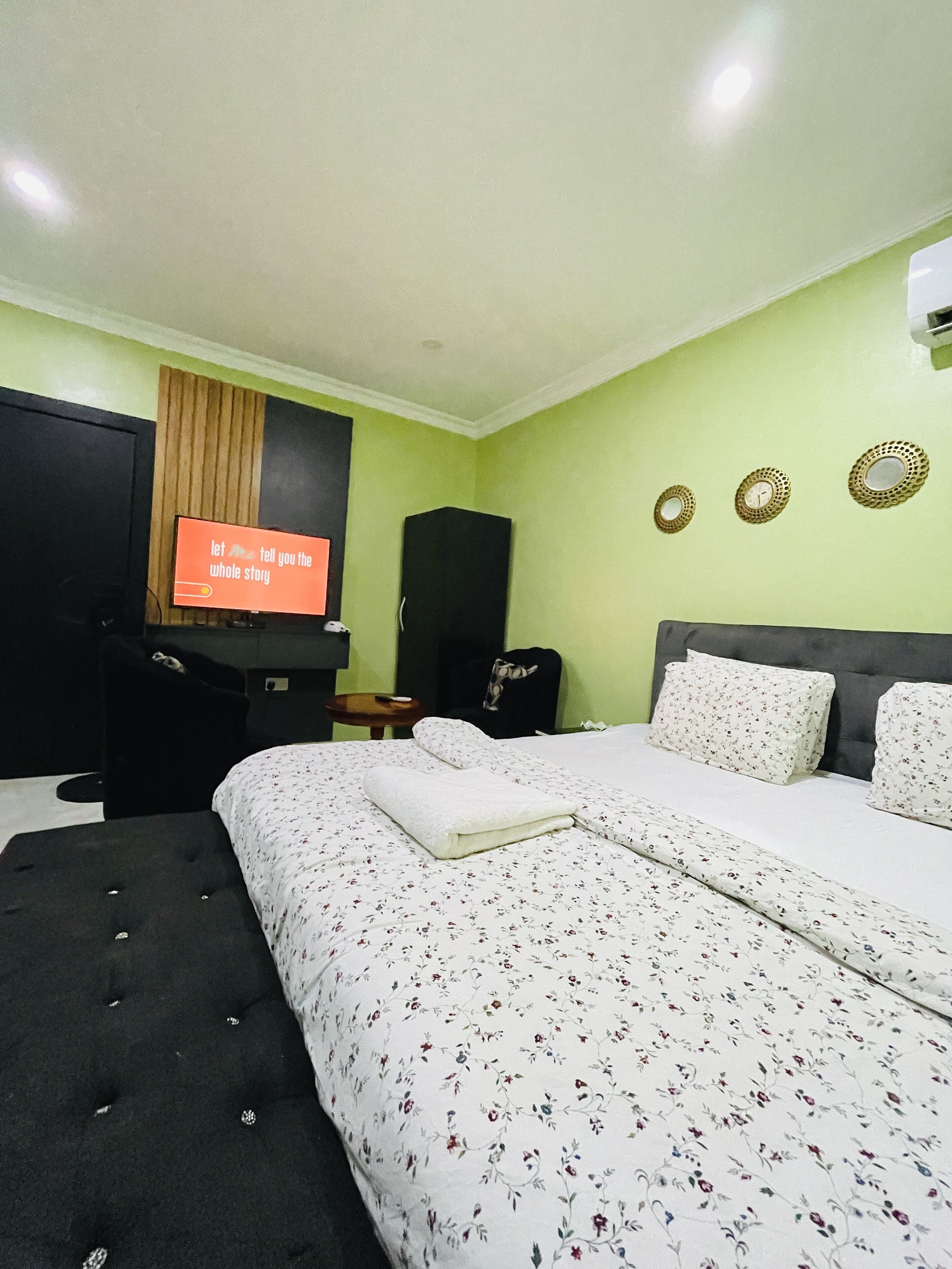 A hotel room with a bed, a TV, a wardrobe, and a small table.
