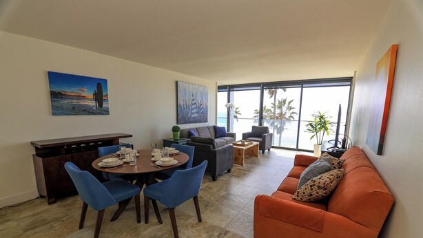 Een moderne woonkamer met een eethoek, grote ramen en uitzicht op de oceaan.