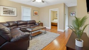 A living room with a leather sofa, a coffee table, a ceiling fan, and a potted plant.