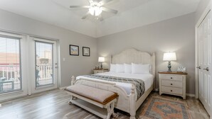 Un dormitorio con cama, banca, mesitas de noche y ventilador de techo.