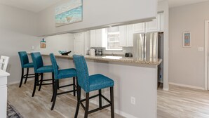Una cocina con una isla central, taburetes de bar y un cuadro sobre la isla.