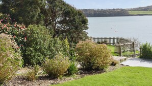 A garden with a wooden fence, a pathway, and a view of a lake. - 3 bedroom accommodation in St Mawes (St Mawes)