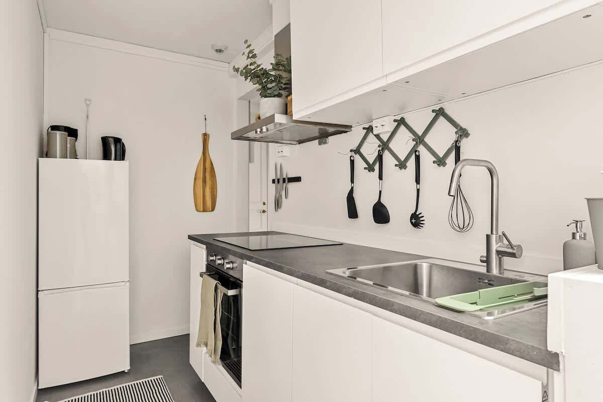 Una cocina moderna con armarios blancos, un lavamanos de acero inoxidable y un horno empotrado.