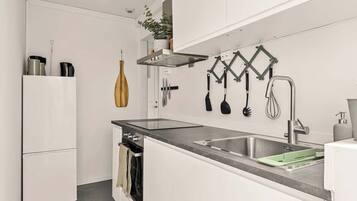 Una cocina moderna con armarios blancos, un lavamanos de acero inoxidable y un horno empotrado.