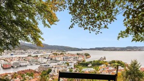 Un banc offrant une vue sur un paysage urbain, avec une rivière, des bâtiments et des collines.