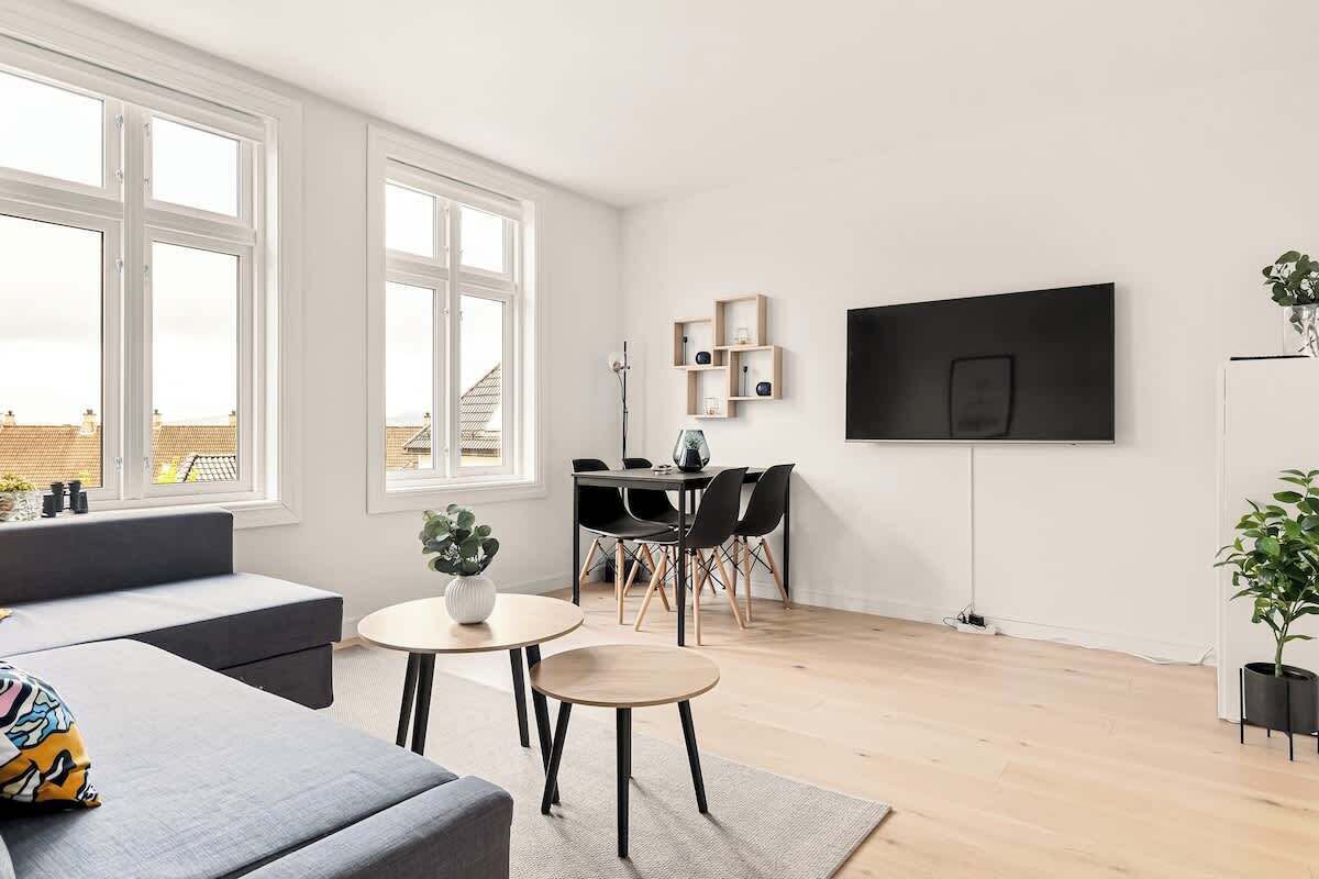 Una sala de estar moderna con un sofá, una mesita redonda y una zona de comedor con sillas.
