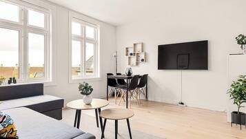Una sala de estar moderna con un sofá, una mesita redonda y una zona de comedor con sillas.