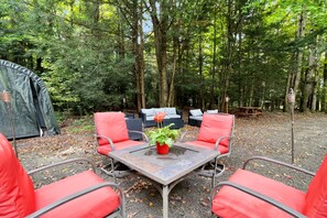An outdoor seating area with a table and chairs, surrounded by trees. - Escape to this all season peaceful getaway. (Arcade)