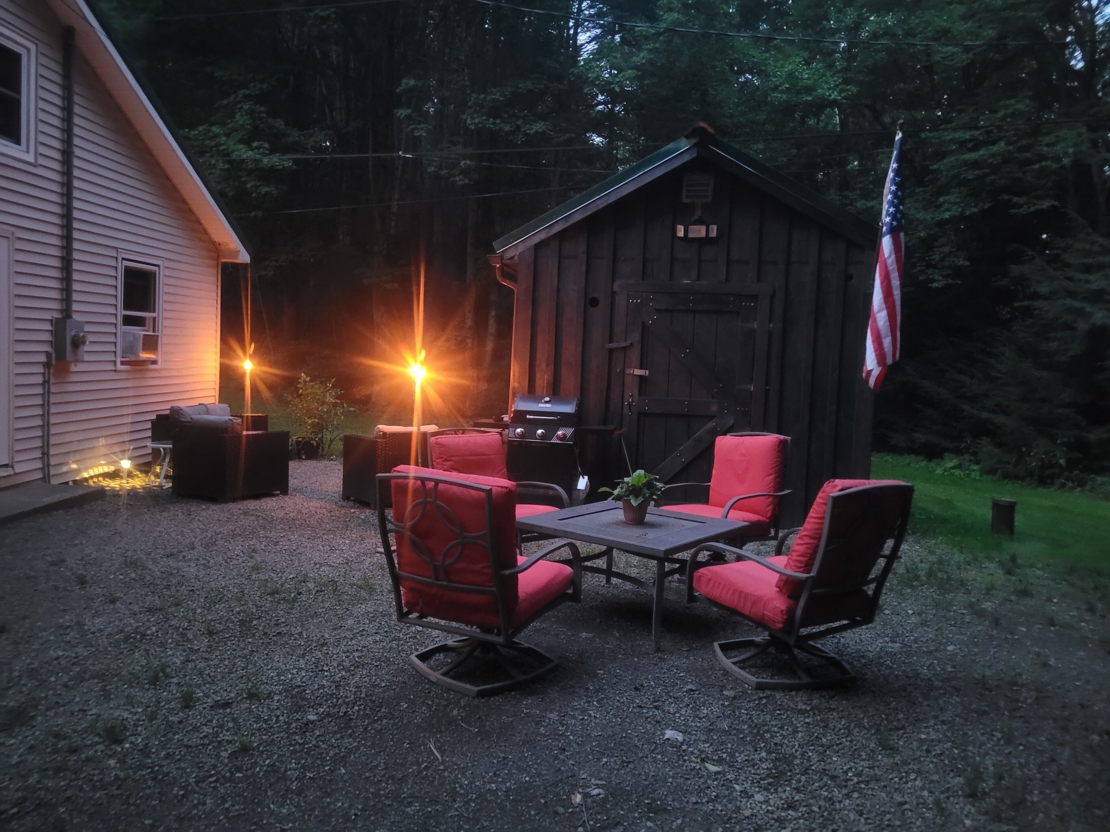 A wooden cabin with a porch, a grill, and an American flag.