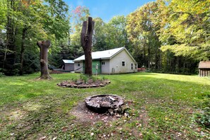 A house with a green roof, surrounded by a wooded area with tall trees and a well-maintained lawn. - Escape to this all season peaceful getaway. (Arcade)