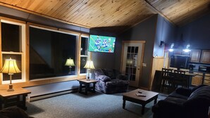 A cozy living room with a television, two lamps, a sofa, and a coffee table. - A short walk to a private beach for swimming boating or fishing  (Arcade)