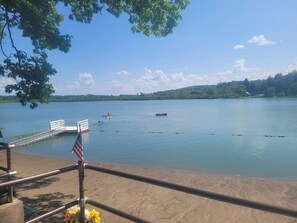 A lakeside view with a dock, a bench, and an American flag. - Escape to this all season peaceful getaway. (Arcade)