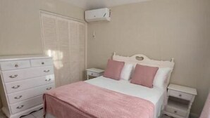 Ein Schlafzimmer mit einem Bett, einem Schminktisch, einem Nachttisch und einem Kleiderschrank.