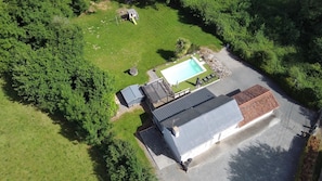 Vue aérienne d’une propriété comprenant une piscine, un petit bâtiment et une cour clôturée.