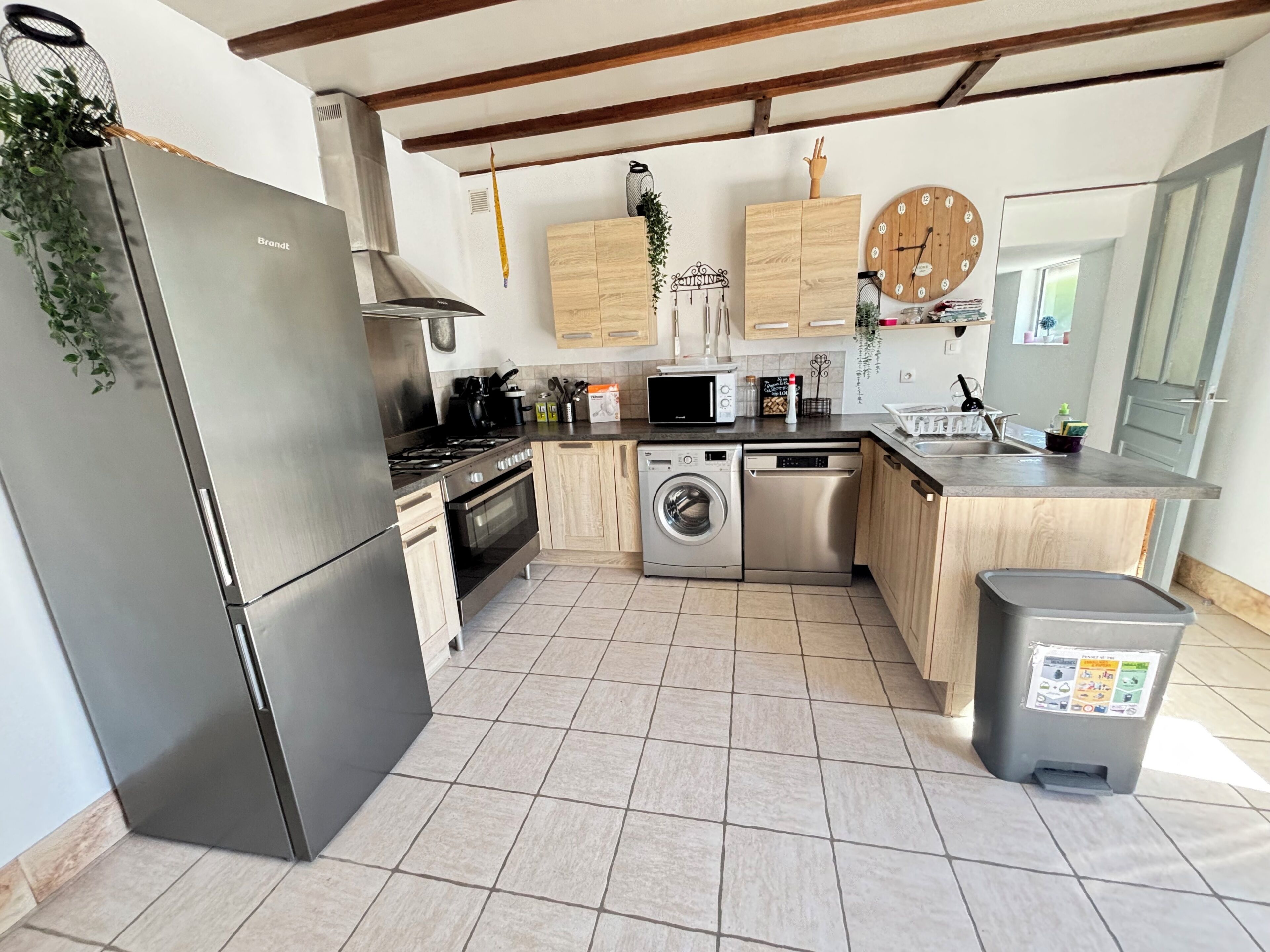 A modern kitchen with stainless steel appliances, wooden cabinets, and a built-in washing machine.