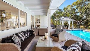Un espacio exterior moderno con piscina, asientos cómodos y un pabellón.